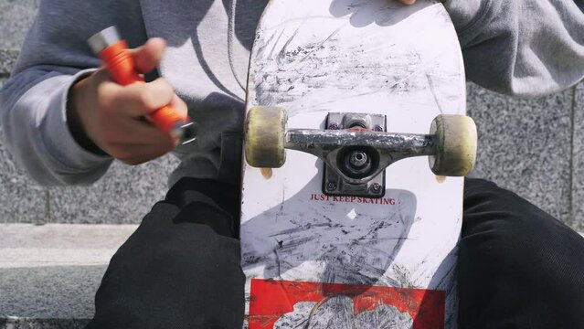 Close-up. Guy with tools screwing Skateboard wheel