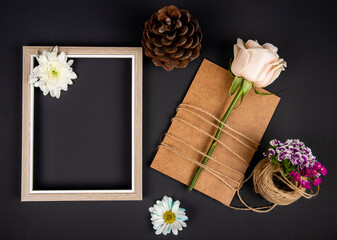 top view of an empty picture frame and brown paper greeting card with white color rose tied with a...