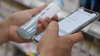 Woman Reading Product Label In Cosmetics Shop Using Mobile Phone Checking Components. Close up. 4K.