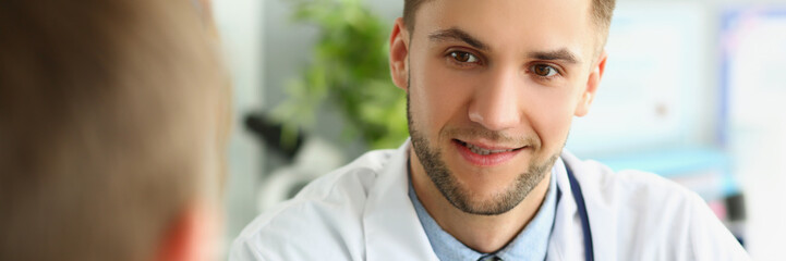 Fototapeta premium Young male doctor listens to a patient, close-up face