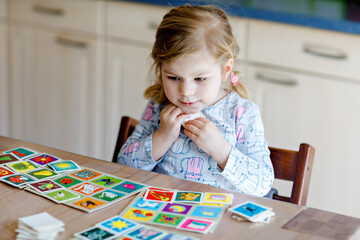 Excited smiling cute toddler girl playing picture card game. Happy healthy child training memory,...