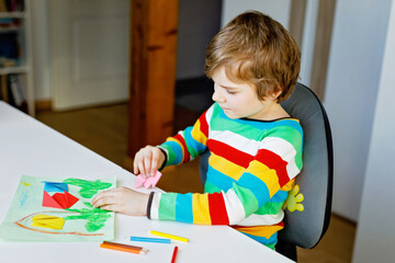 Little kid boy making paper origami tulip flowers for a postcard for mother's day or birthday. Cute...