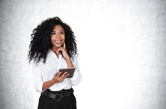 African businesswoman with tablet, smiling on grey wall background. Copy space