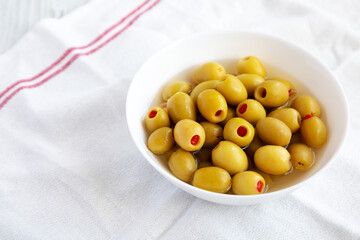 Marinated Green Olives with Pimento Peppers in a Bowl, side view. Space for text.