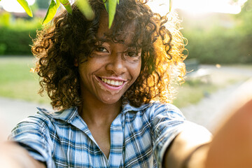 young biracial woman taking selfie on sunset outside, female person with genetic vitiligo smiling at the camera, happy people and body positive concepts