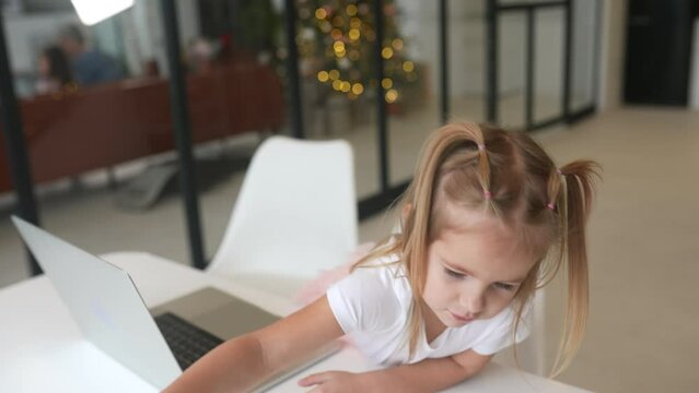 Little girl using tablet computer sitting at table