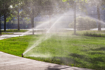 Obraz premium Automatic sprinklers watering grass. Garden Watering Systems. Irrigation System Watering the green grass