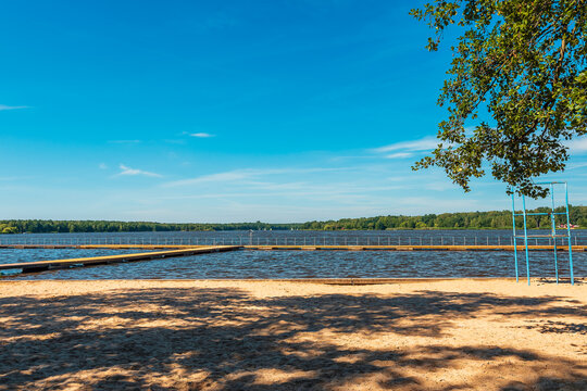 view of the paprocańskie lake in Tychy. Wooden platforms in the foreground. Water plants and sailboats. A beautiful sunny day.  Sandy beach in light and shade