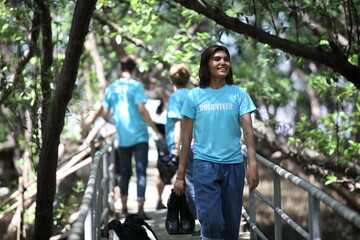 Obraz premium Happy volunteer working , volunteering, charity, cleaning, people and ecology concept - group of happy volunteers with garbage bags cleaning area in park