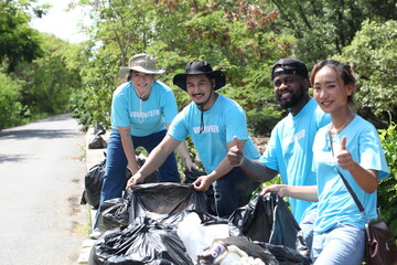 Happy volunteer working , volunteering, charity, cleaning, people and ecology concept - group of happy volunteers with garbage bags cleaning area in park