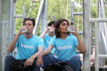 Happy volunteer working , volunteering, charity, cleaning, people and ecology concept - group of happy volunteers with garbage bags cleaning area in park