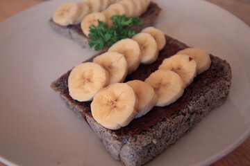 Whole grain bread loaf with chocolate spread topped with banana slices for a healthy vegan breakfast and a healthy sustainable lifestyle