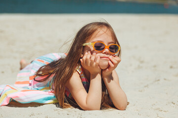 little girl child with down syndrome lies on the beach. normal life of children with down syndrome