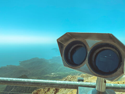 A Viewing Platform With Binoculars With Large Black Lenses Against The Background Of A Sunny Blue Sky. Environment Magnifier. Panoramic Binoculars For Tourists