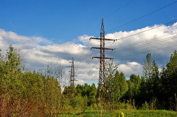 a high-voltage power line runs through the forest against the blue sky