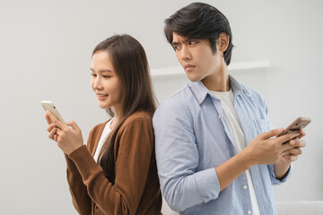 Infidelity, suspicion asian young couple love standing back to back, husband watching his wife...