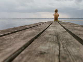 the concept of loneliness, sadness. a small child sits alone on a bridge