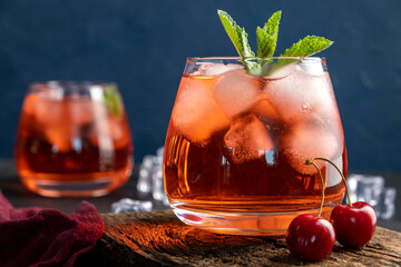 Cherry cocktail in glass on blue background. Summer iced beverage.