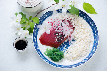 Plate with smoked tuna fillet and steamed rice on a white stone background, elevated view, horizontal shot