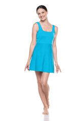 a young barefeet happy woman in a short blue dress posing on white background