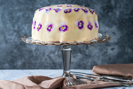 Rainbow cake covered with marzipan and decorated with edible viola flowers