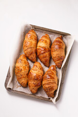 crispy croissants in a metal baking sheets on a white background, top view