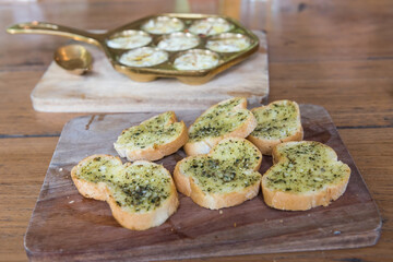 Crispy toasted bread with garlic butter and dill on wooden plate