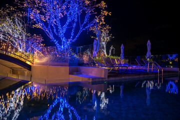 Light up decoration on bridge and trees at night pool
