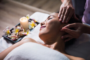 Ayurvedic face and ear Thai massage with oil to woman in spa