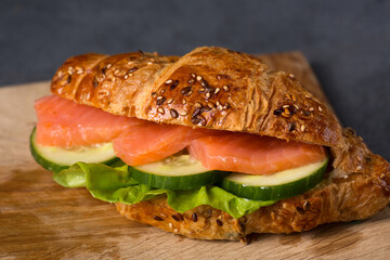 Croissant with salmon and cucumber, close-up