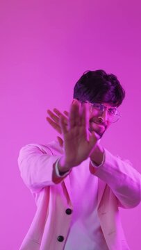 No gesture. Stop enough. Bad idea. Neon color light displeased annoyed man showing refusal disagreement isolated on pink free space vertical background.