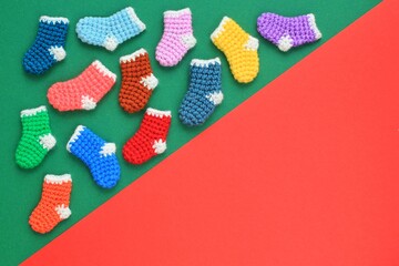 Winter christmas colourful crochet knitted socks with space for text on green red background. Stockings gift New Year season sale concept. Top view flat lay out idea for present decor postcard, banner