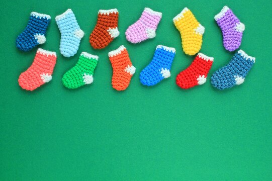 Winter christmas colourful crochet knitted socks with copyspace for text on green background. Stockings gift New Year season sale concept. Top view flat lay out idea for present decor postcard, banner