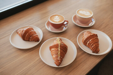 Millennial man and woman are talking in a cafe with a cup of coffee and croissant.