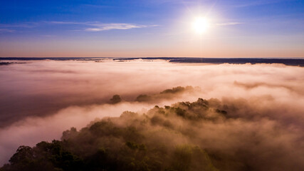 Aerial  view of a beautiful summer  landscape with a fog while dawn.  Photo from drone of a foggy landscape in spring. Top view to land while sunrise. Sun is above the horizon