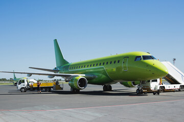 A green plane at the airport, after landing. Unloading of baggage and passengers after the plane...