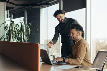 Experienced colleague explaining to young coworker business project strategy at contemporary office, copy space