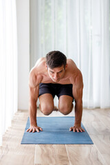 Fototapeta na wymiar Young man doing strength pilates or yoga workout in the morning
