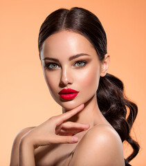 Stunning brunette girl with long black hair.  Beautiful white girl with a red lipstick on lips. Closeup face of young beautiful woman with a healthy clean skin. Pretty woman with bright makeup - obrazy, fototapety, plakaty