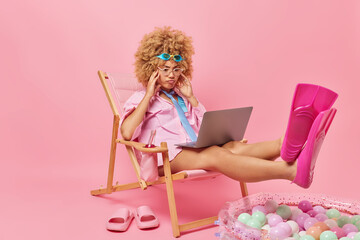 Serious woman with curly hair wears goggles on forehead formal shirt tie and flippers watches film...