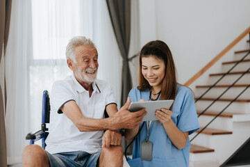 Obraz premium Asian nurse and senior man looking medical record on digital tablet at home. Old man and nurse using digital tablet together to looking health plan. Senior care