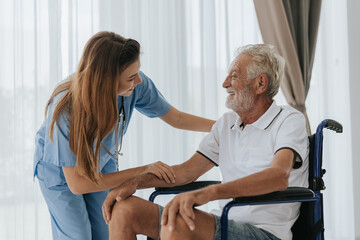 Obraz premium Young asian nurse helping senior man at home. Elderly man sitting on wheelchair and talking with young docter in house. Senior health care.