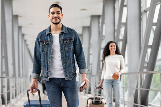 Smiling Middle Eastern Man And Woman Walking With Luggage At Airport