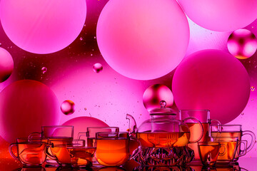 transparent teapot with tea glasses on a colored background