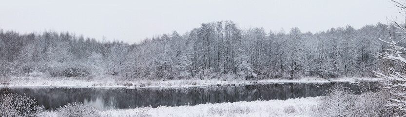 Winter landscape, Christmas and New Year. Snow-covered trees are reflected in the forest river