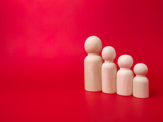 Wooden figures lined up according to their respective heights on red background with copy space.