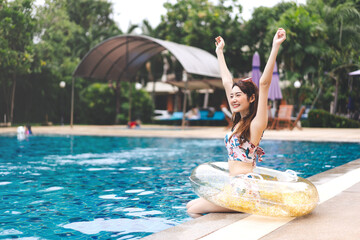 Raised hand young adult asian woman at hotel swimming pool holidays summer travel