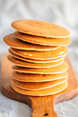 Pancakes for breakfast. Cover with pancakes. A stack of pancakes on a wooden board with honey. Honey pours on pancakes. Dessert. Favorite breakfast. Beautiful food cover.American breakfast. 