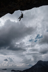 Obraz premium Climber hanging on the rope on then rock on cloudy day. Kalymnos island, Greece.