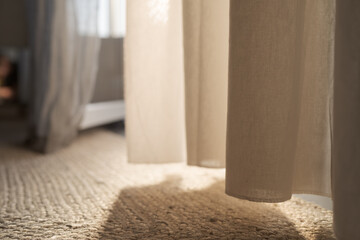 Closeup photo of jute rug on a floor with curtains on background with warm sun light